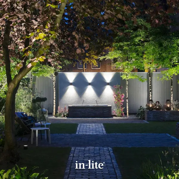 in-lite atmospheric garden lighting. in-lite ACE UP DOWN 12v Outdoor Wall Lights symetrically positioned on rendered wall with water fountain trough below. The short and slim light fixtures are illuminating the wall facade and water fountain trough with focused light pools upwards and downwards.