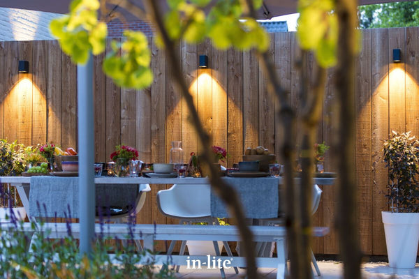 Atmospheric lighting by in-lite. ACE DOWN 12v outdoor wall luminaires positioned higher along a fence, washing the fence with targeted beams of downward warm white light.