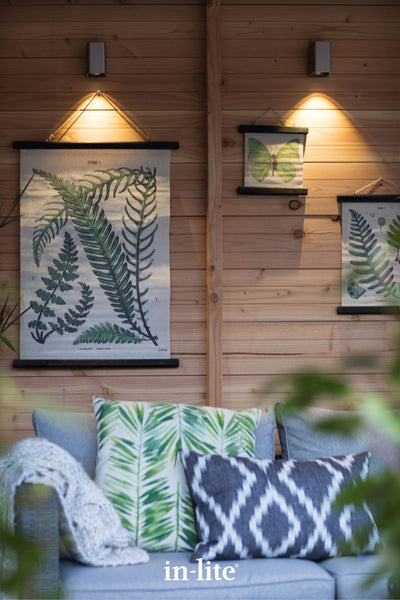 Atmospheric lighting by in-lite. ACE DOWN Rose Silver 12v outdoor wall luminaires positioned higher on a timber wall, illuminating wall art with targeted beams of downward warm white light.