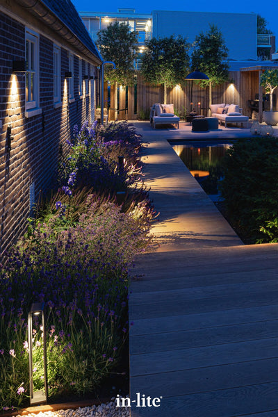 Atmospheric lighting by in-lite. ACE HIGH 12v outdoor bollard luminaires illuminating pathways with targeted light beams along modern landscape deck walkways.