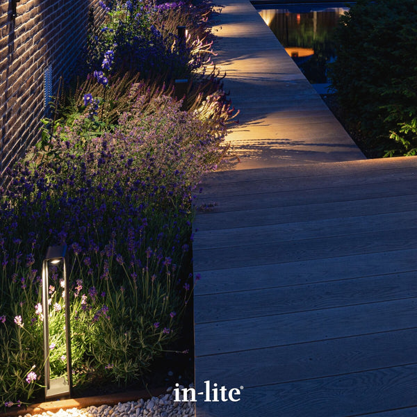 Atmospheric lighting by in-lite. ACE HIGH 12v outdoor lighting fixtures illuminating paths and walkways with targeted light beams along modern landscape decking.