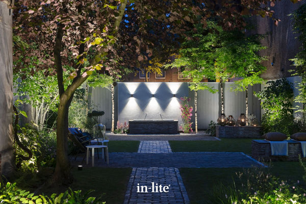 Atmospheric lighting by in-lite. ACE UP DOWN 12v outdoor facade lighting fixtures illuminating rendered wall in decoratively landscaped contemporary garden.