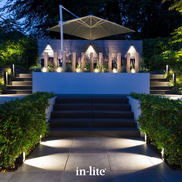 Atmospheric lighting by in-lite. ACE 12v outdoor lighting fixtures illuminating a patio, pathways, steps and surfaces from the borders in modern landscape.