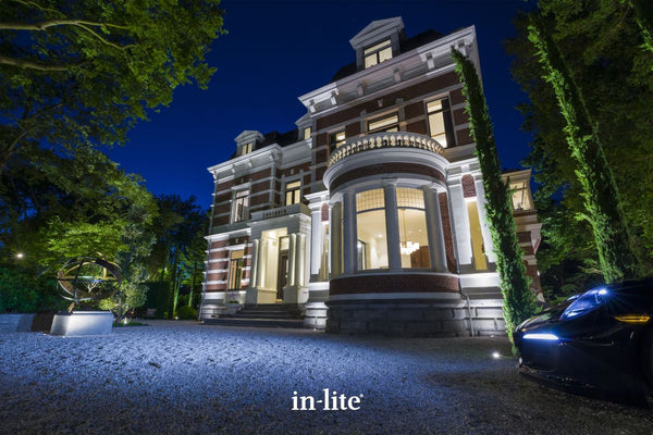 Atmospheric lighting by in-lite. BIG FLUX NARROW 12v outdoor ground recessed vertical lighting fixtures projecting narrow light beams upwards on architectural wall facades of high end property, Villa Zonnehoek.