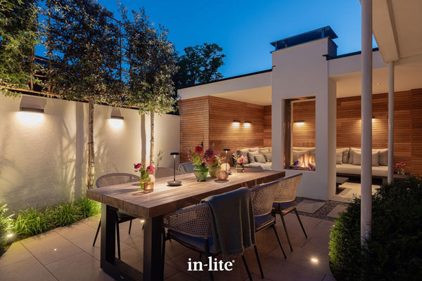 Atmospheric lighting by in-lite. EVO DOWN DARK 12v outdoor wall light fixtures projecting a downward-facing glow on architectural style walls in modern outdoor living patio space.
