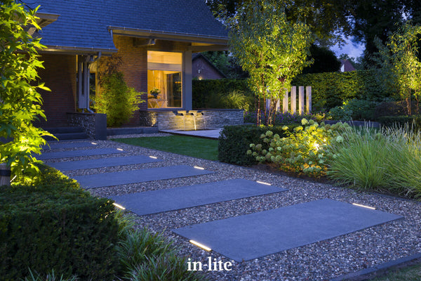 in-lite EVO GROUND 300 12v Outdoor linear ground lights installed providing indicative illumination each side of large paving slabs for safety and ambiance in modern landscape.