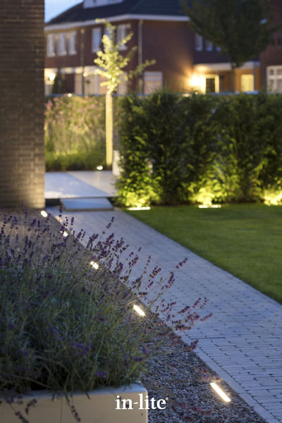 in-lite EVO GROUND 300 12v Outdoor linear ground lights installed providing indicative illumination along block paved pathway in a modern landscape.