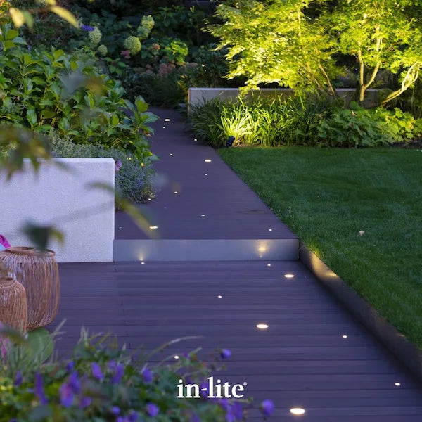 in-lite atmospheric garden lighting. In-lite FUSION 12v Outdoor decking lights recessed in deck boards, installed in various positions around the decking. The In-lite FUSION decking lights are illuminating in a starry night pattern around the decking space in a modern contemporary and lush garden.